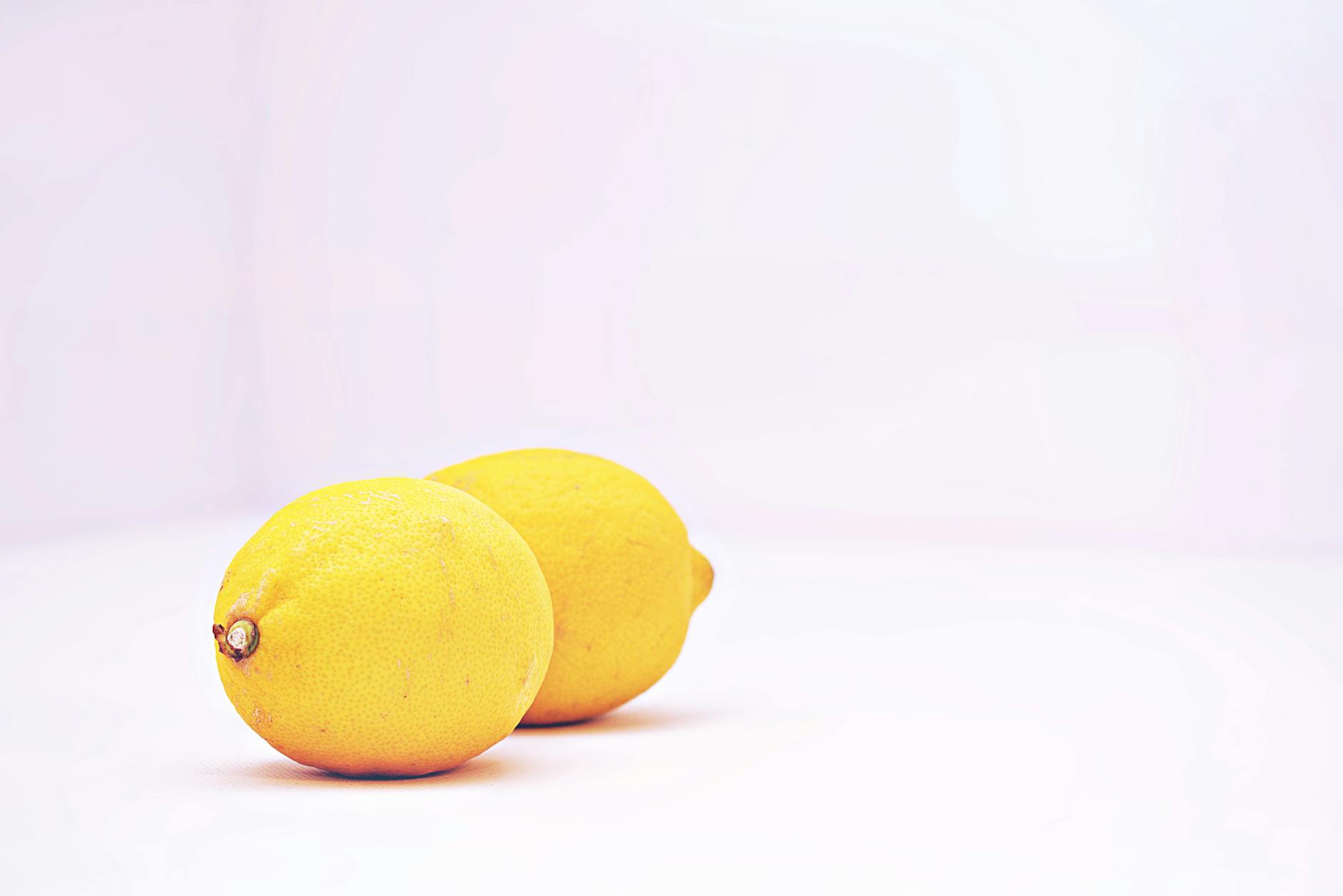 Two vibrant lemons against a minimalistic white background, symbolizing fresh sensation and renewal