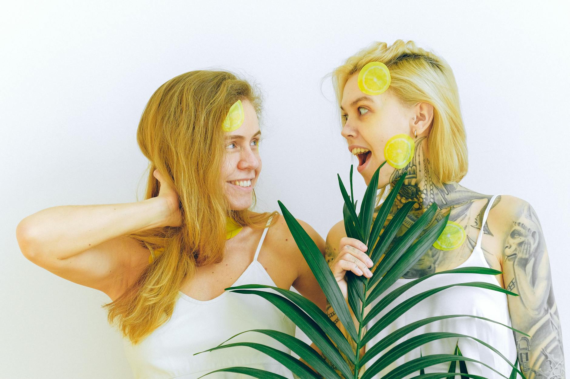 Two women smiling together with lemon slices, expressing joy and intimacy indoors