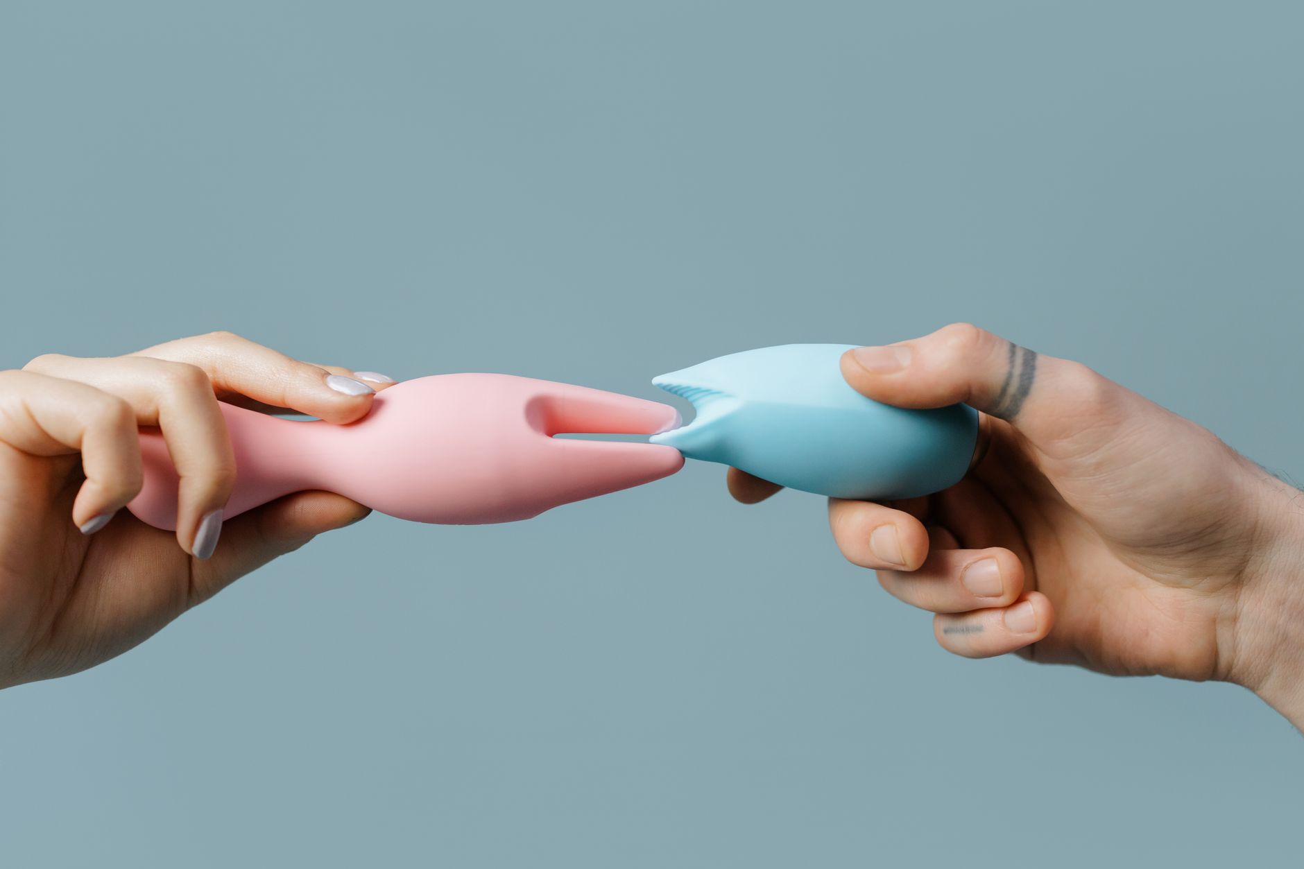 Woman holding a blue clitoral vibrator with a contemplative expression