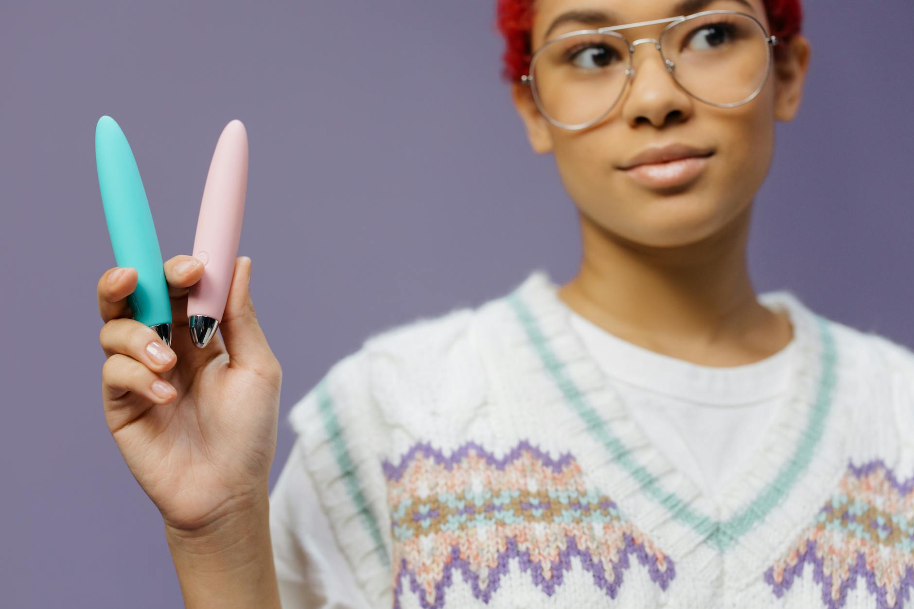 Woman holding colorful vibrators, one resembling a lemon, against a purple background