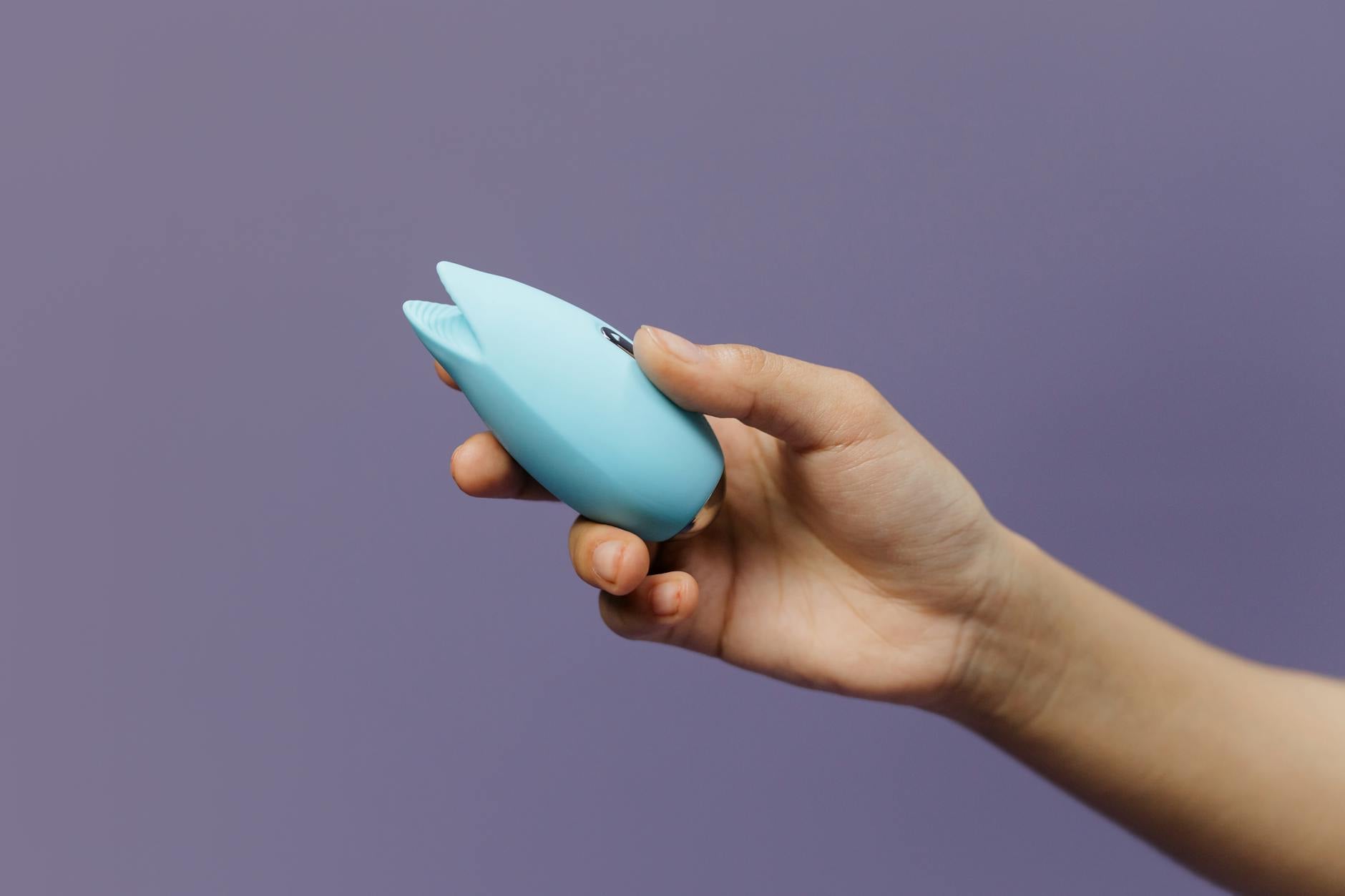 A blue silicone vibrator held in hand, symbolizing gentle self-care and reconnection with pleasure after depression