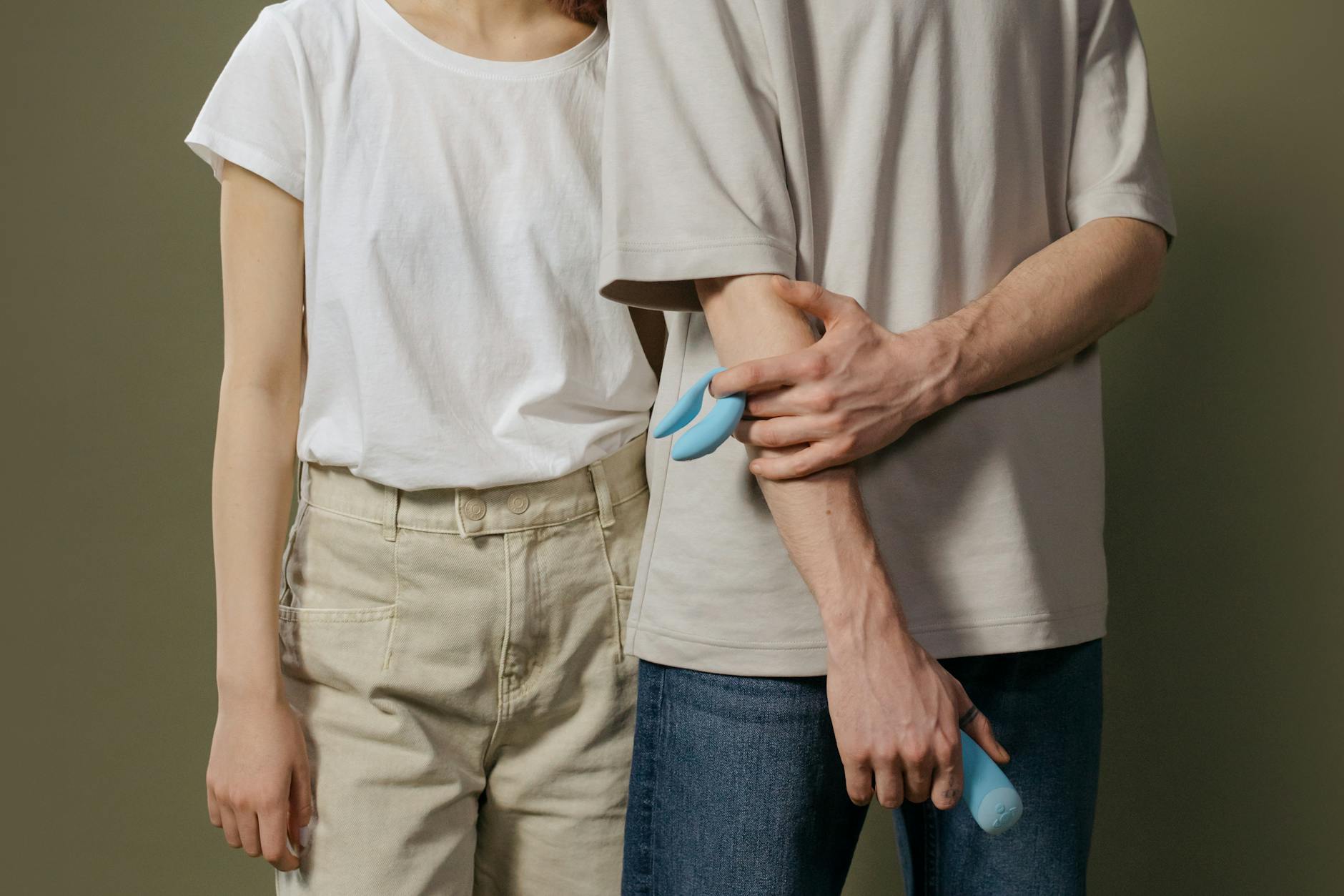 A couple standing close together indoors, exploring intimacy and connection with a vibrator
